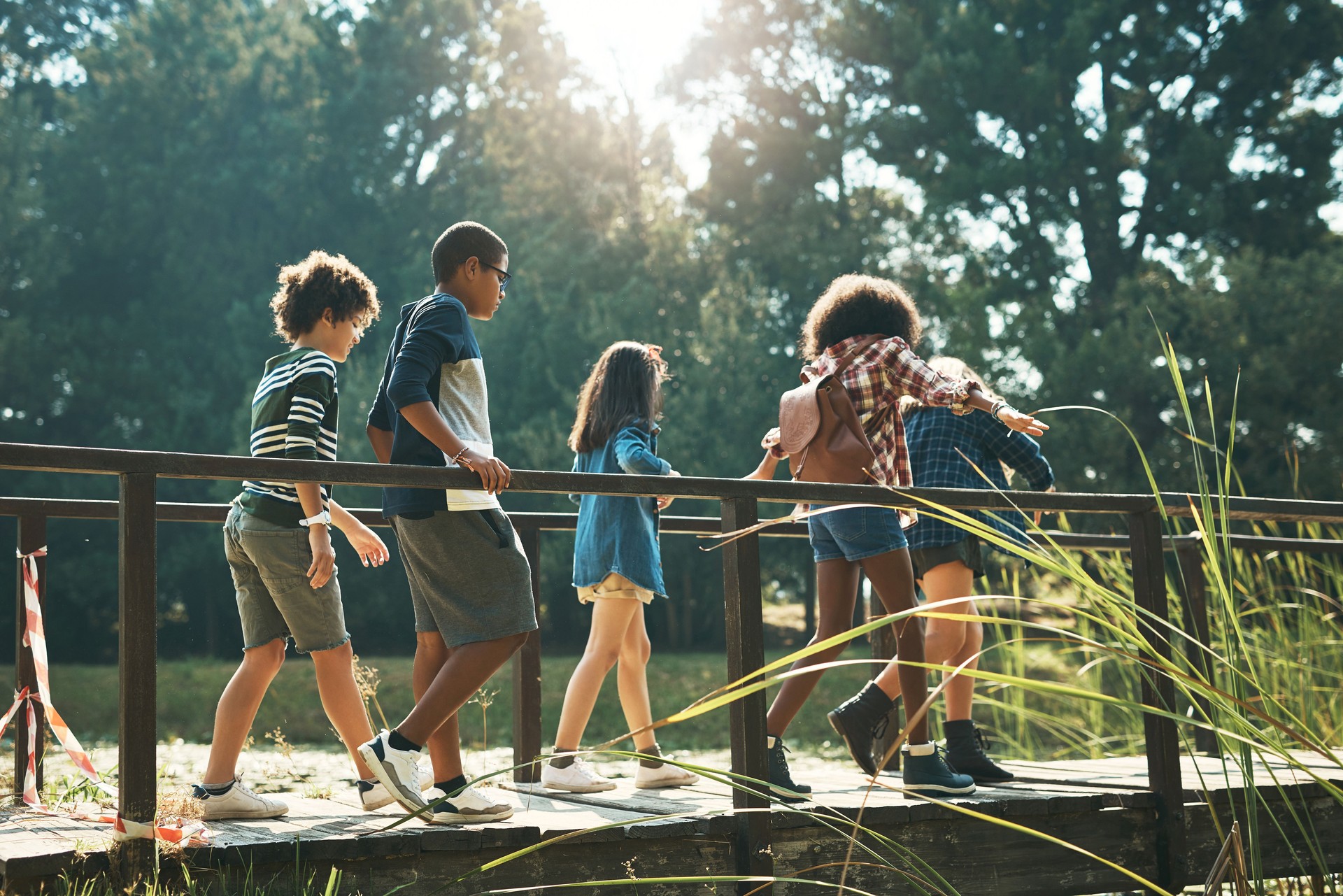 Shot of a group of teenagers walking across a bridge in nature at summer camp