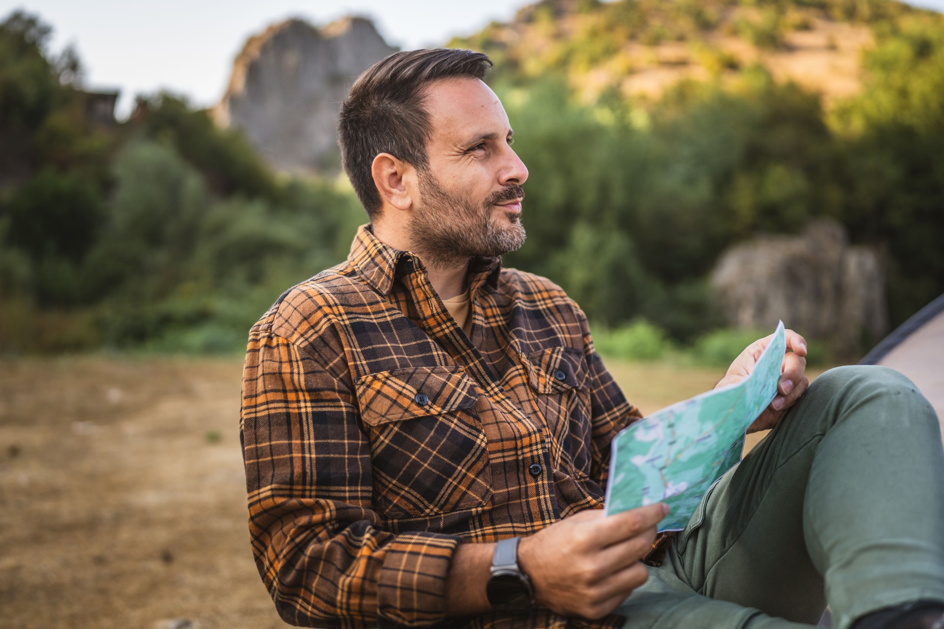 Adult man hiker sit on chair and read map look for the right way