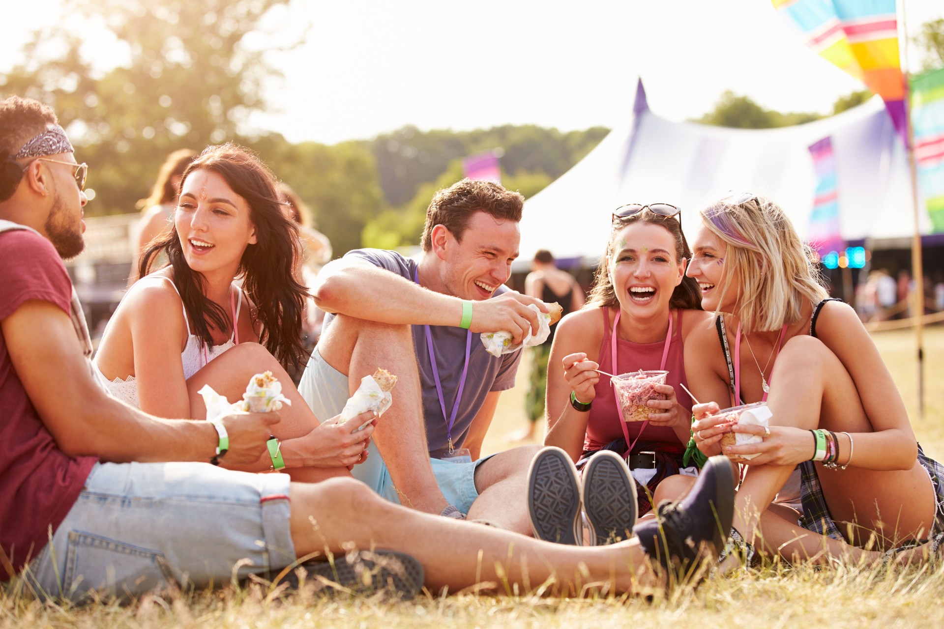 Friends sitting on the grass eating at a music festival